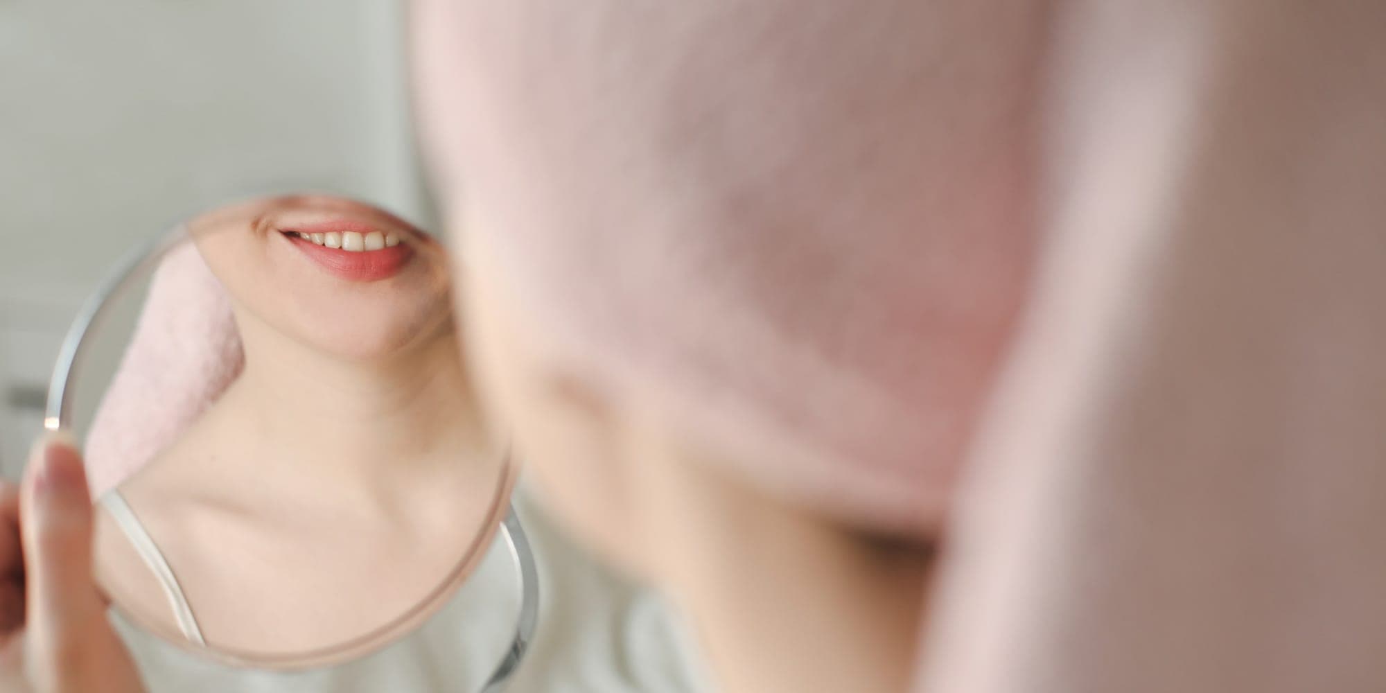 Mujer sonriendo con una toalla en la cabeza durante su rutina de skincare